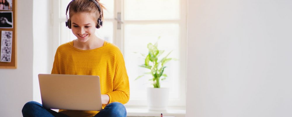 A,Young,Female,Student,Sitting,At,The,Table,,Using,Headphones