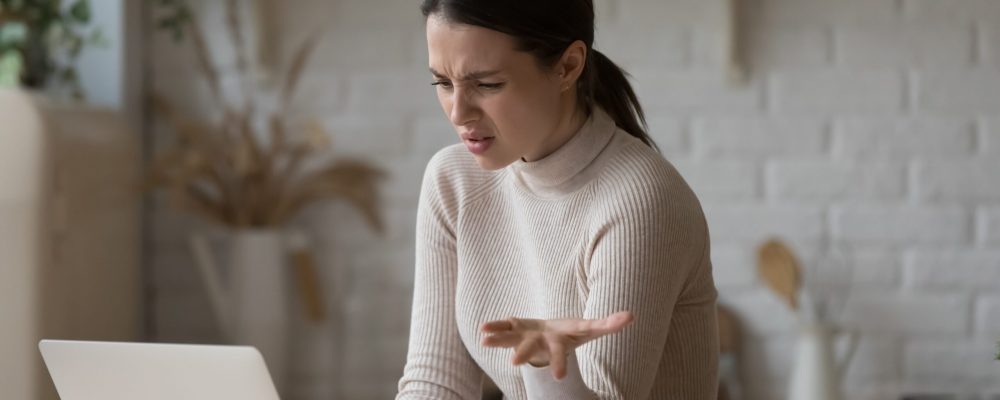 Irritated,Woman,Sit,At,Table,Staring,At,Laptop,Screen,Feels