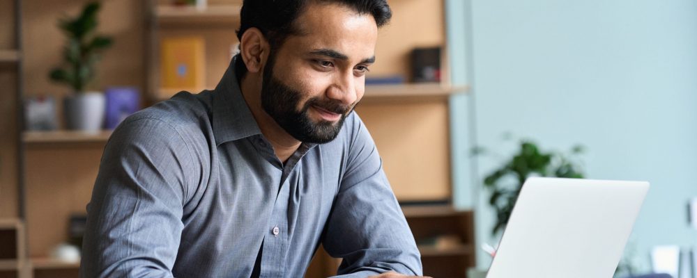 Smiling,Indian,Business,Man,Working,On,Laptop,At,Home,Office.
