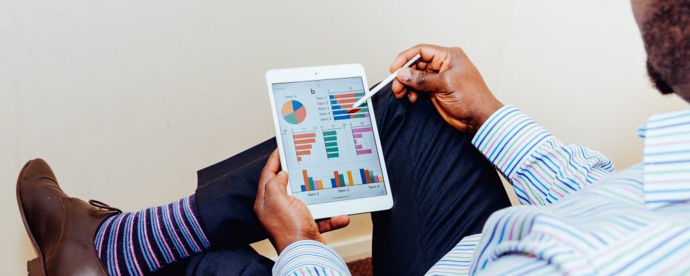 A man reviews some charts and graphs on an iPad.