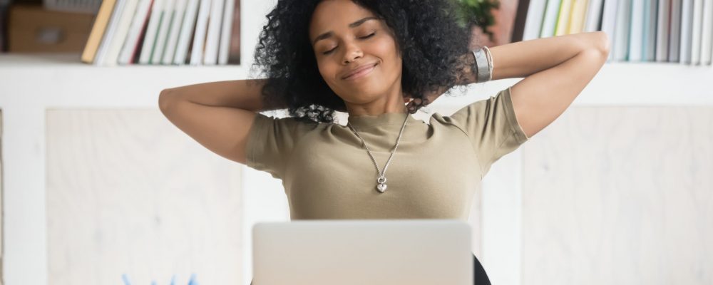Calm,African,American,Businesswoman,With,Hands,Behind,Head,Relaxing,In Relaxed woman in front of laptop with hands behind head.