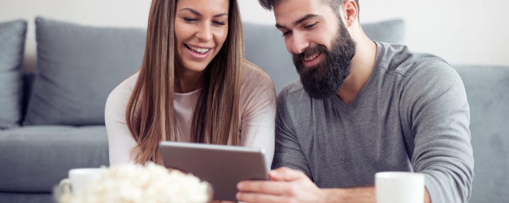 Happy,Couple,Surfing,On,A,Tablet,While,Enjoying,Their,Morning