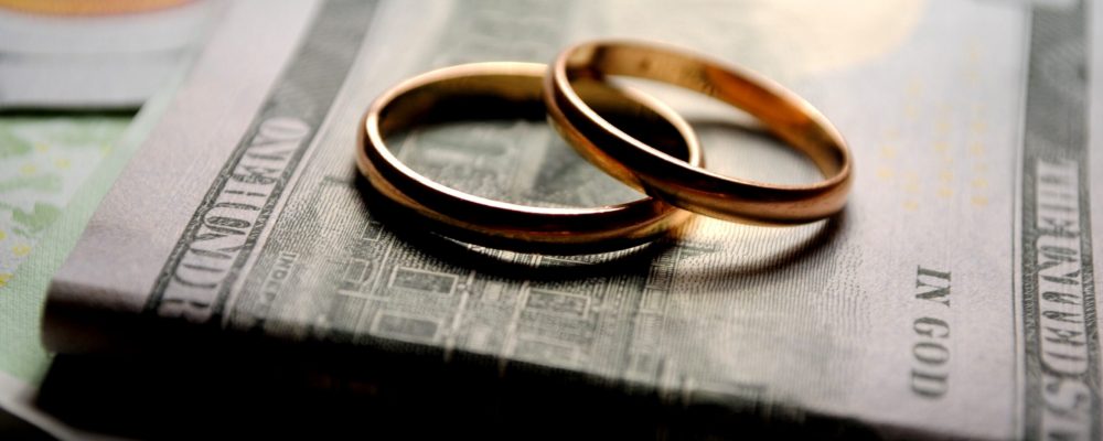 wedding rings on top of a stack of dollars