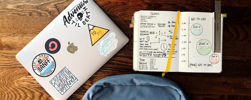 matt-ragland-02z1I7gv4ao-unsplash Backpack and laptop sit on a wood table.