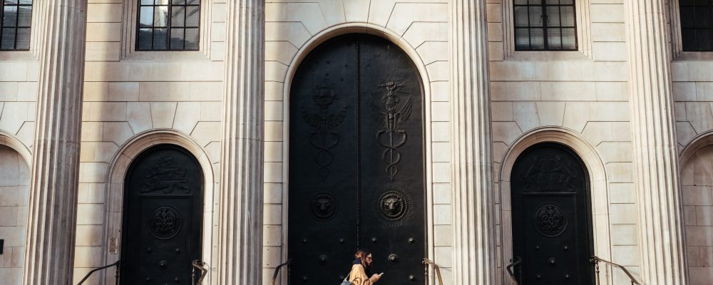robert-bye-jeF-vyxytb4-unsplash (1) Woman walks in front of a bank entrance.
