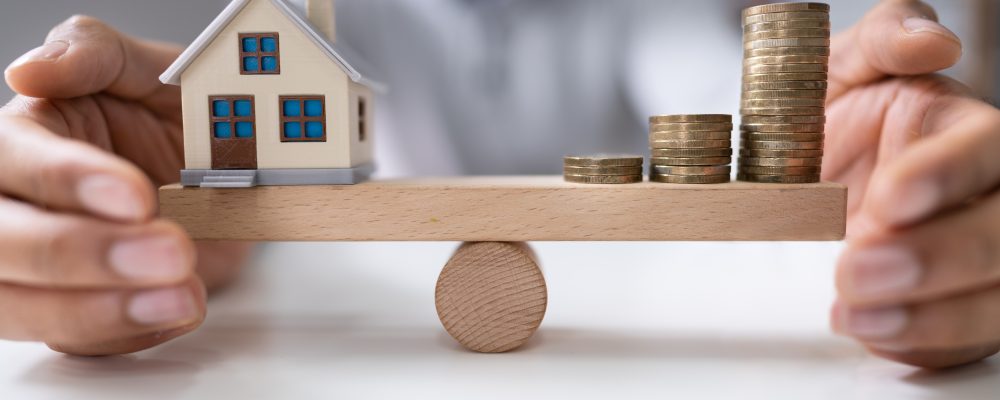 Businessperson's,Hand,Protecting,Balance,Between,House,Model,And,Increasing,Stacked