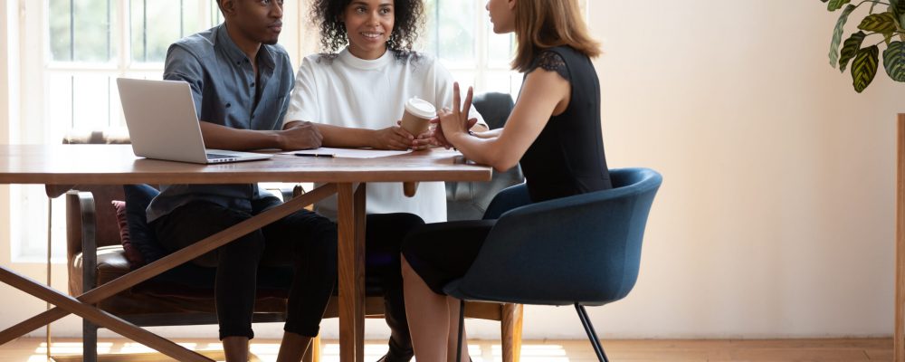 Young,African,American,Husband,And,Wife,Sit,At,Desk,Talk Young,African,American,Husband,And,Wife,Sit,At,Desk,Talk